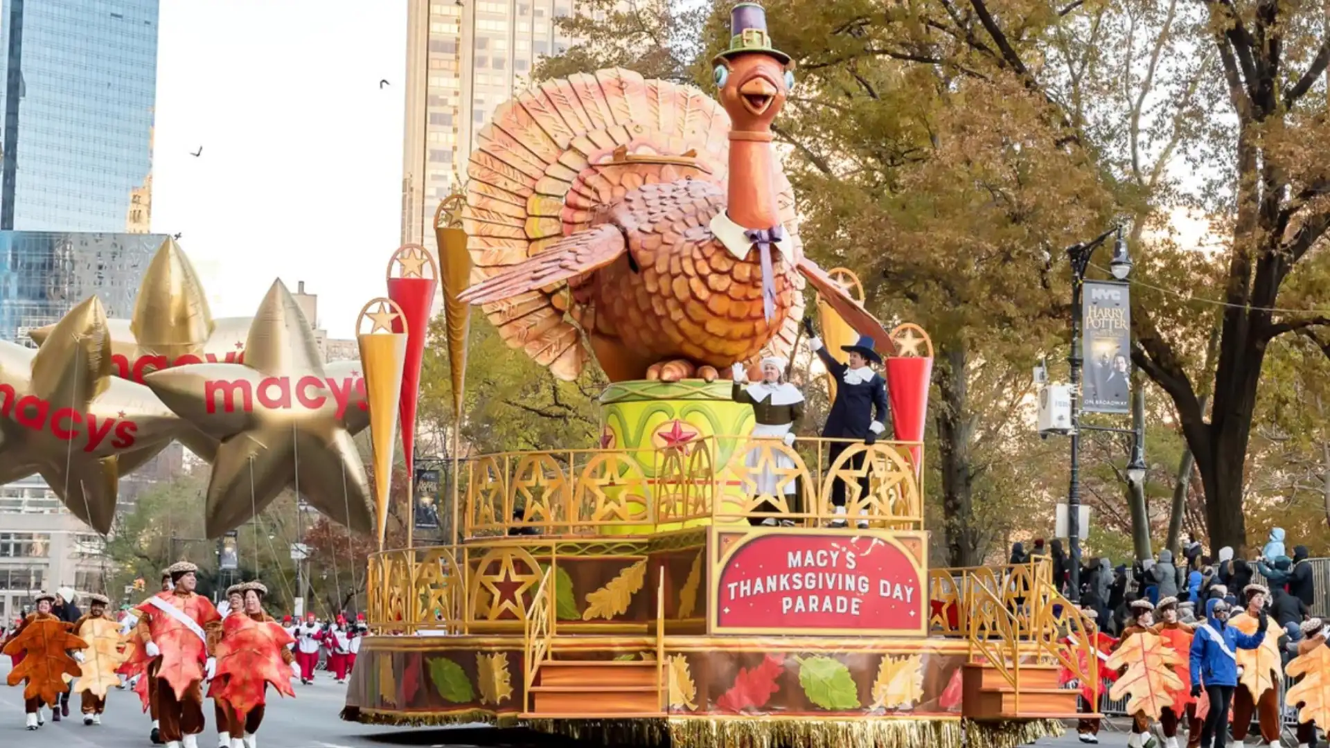 Macy’s Thanksgiving Day parade float with giant turkey and performers in festive costumes on street