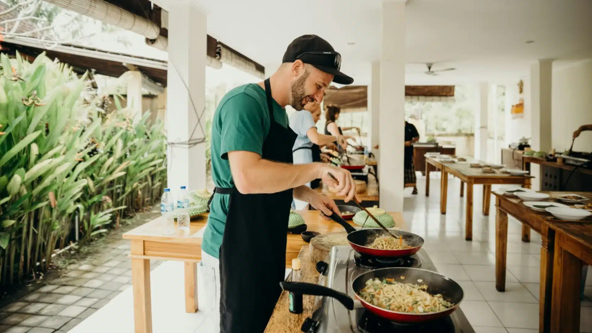 Man cooking in outdoor kitchen during a cook-off competition with multiple dishes being prepared