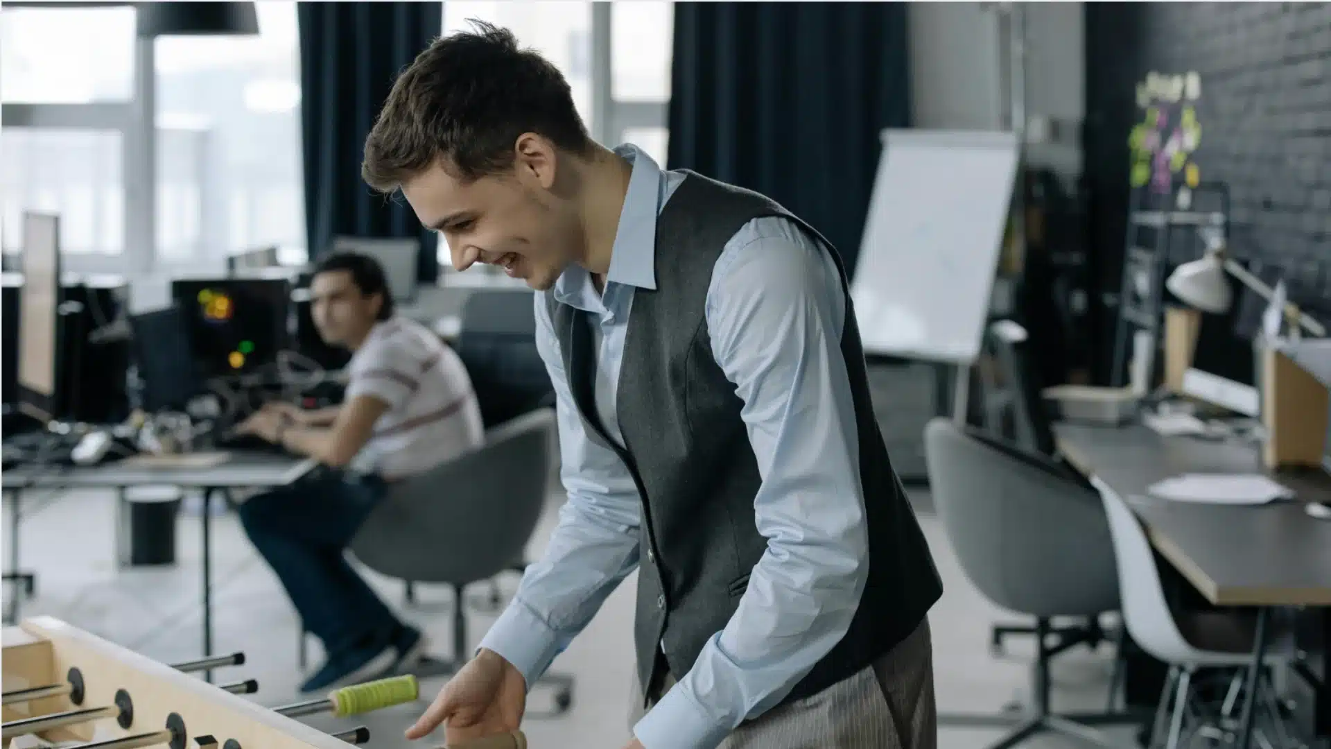 Office coworkers playing foosball game together in modern workspace during break time