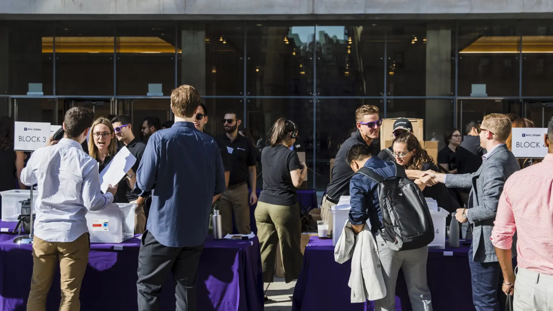 Orientation program with attendees registering and networking around tables outside modern building