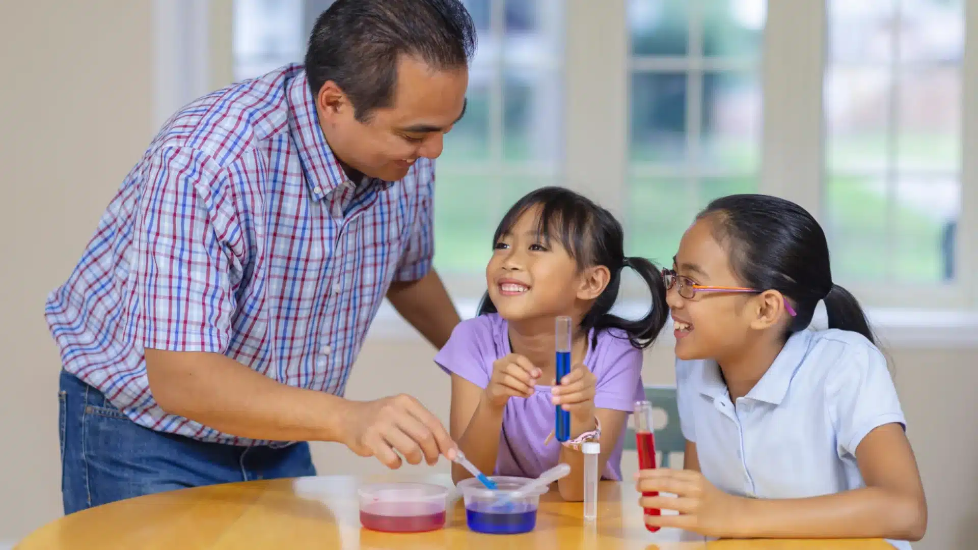 Parent guiding kids with fun science experiment using test tubes, learning together during STEM activity