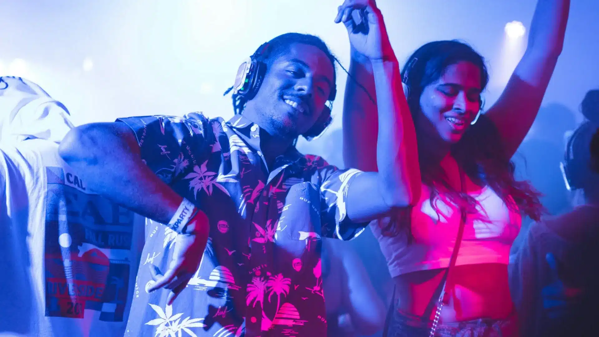 People dancing with headphones at silent disco party under colorful lights in lively nightlife setting