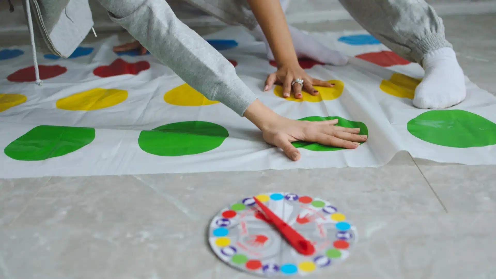Person playing Twister as escape room activity with colorful mat and spinner during fun group activity