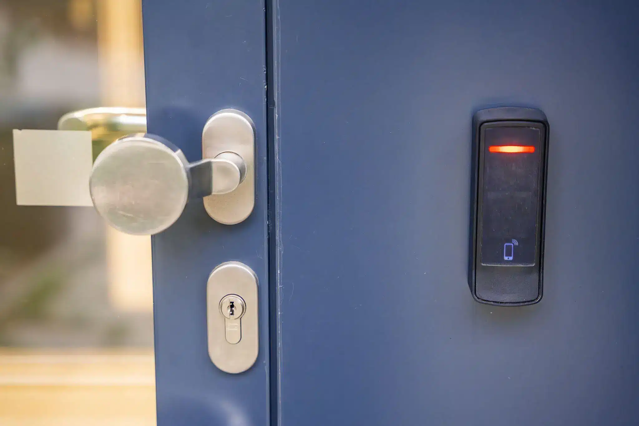 Metal door handle and keyhole with electronic lock on blue door