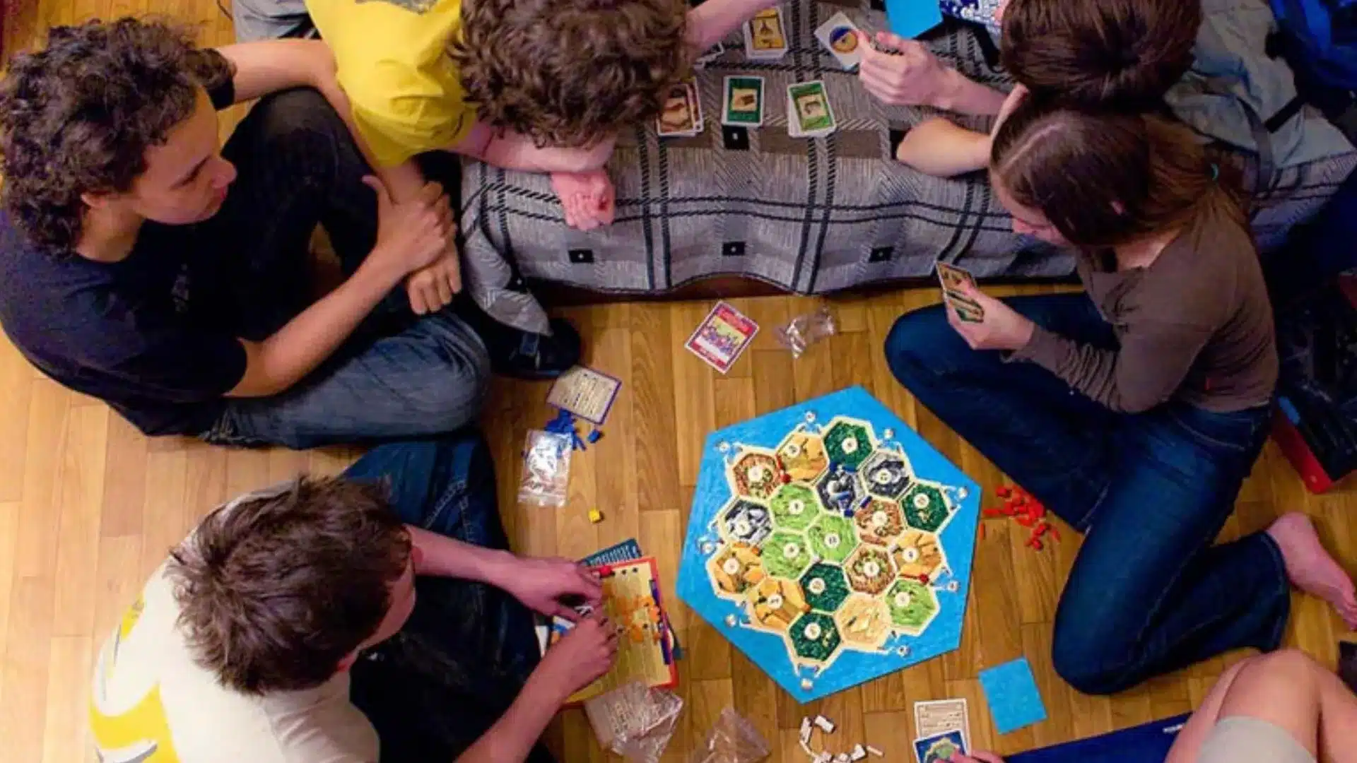 Students sitting on floor playing board game together, focused on strategy and teamwork during a fun school event