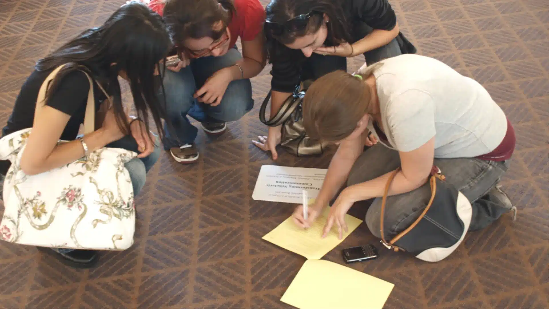 Students working together on a scavenger hunt, reading clues and writing answers while collaborating on the floor