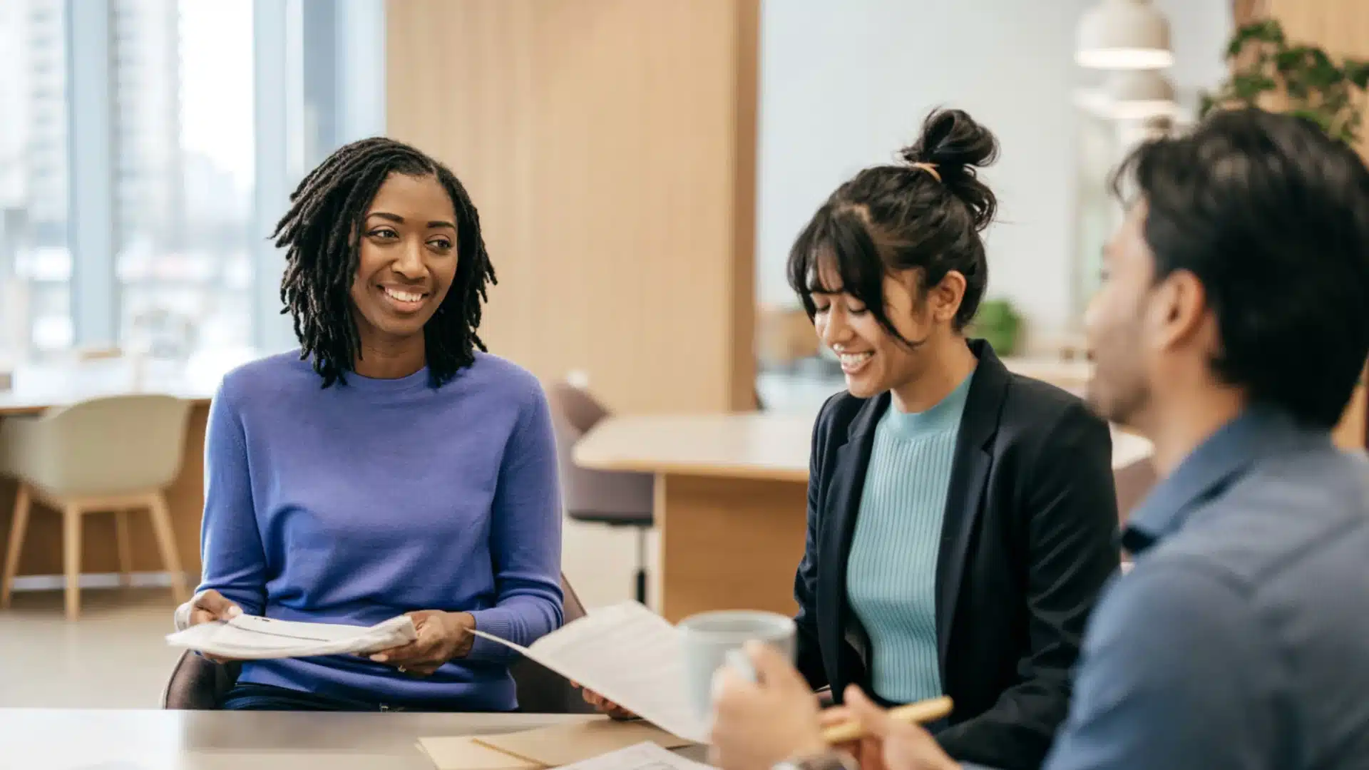 Teachers and staff smiling during a school planning meeting, discussing ideas and reviewing documents together