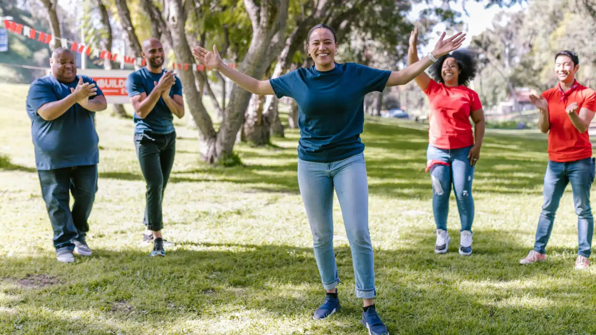 Team celebrating outdoor activity with group cheering and smiling in park team building event