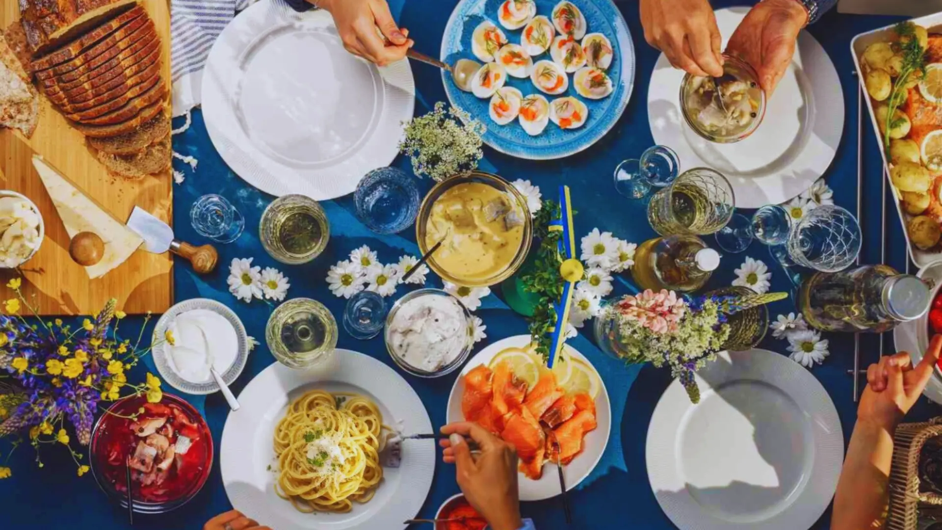 Top view of a dinner table with gourmet dishes, drinks, and flowers during an elegant themed meal