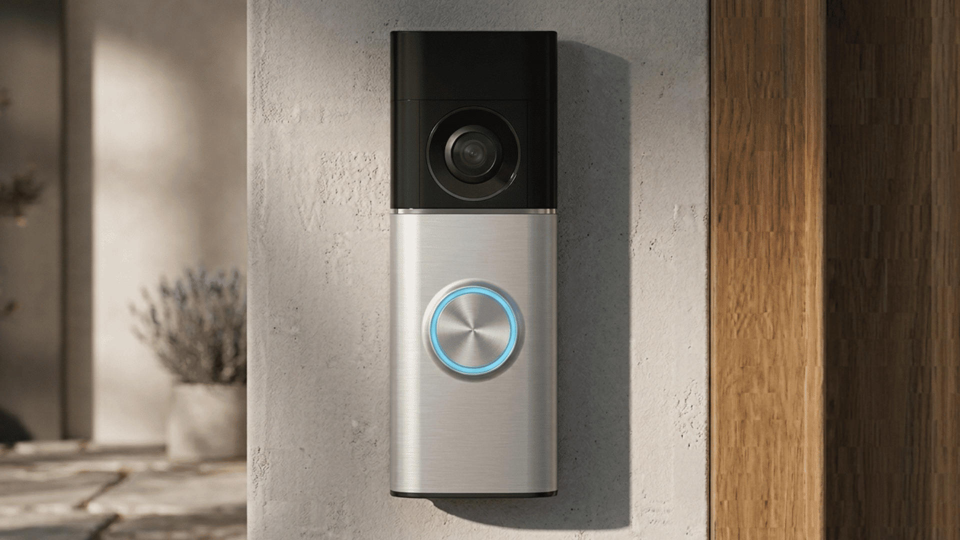 A video doorbell mounted on a wall with a glowing circular button and a camera lens above it
