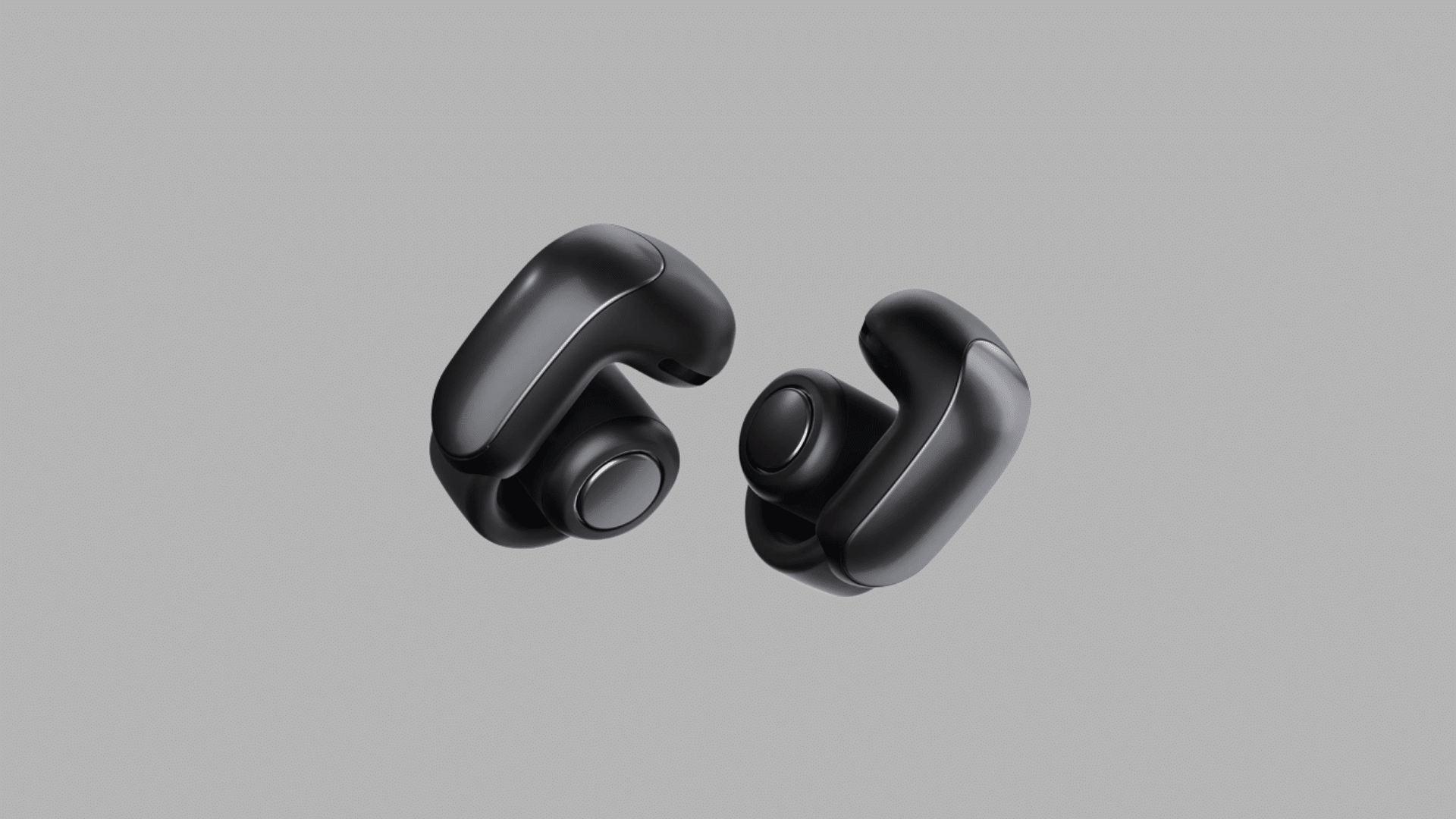 Black Bose Ultra Open Earbuds shown against a plain gray background, highlighting their sleek design