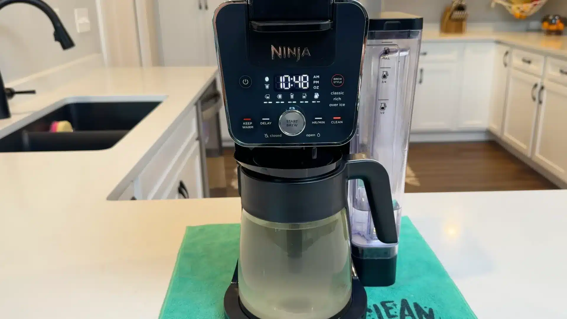 Coffee maker running descaling cycle with cloudy water collecting inside glass carafe