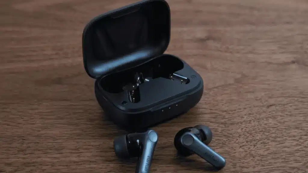 Earfun Air Pro 4 earbuds and charging case on a dark wood table