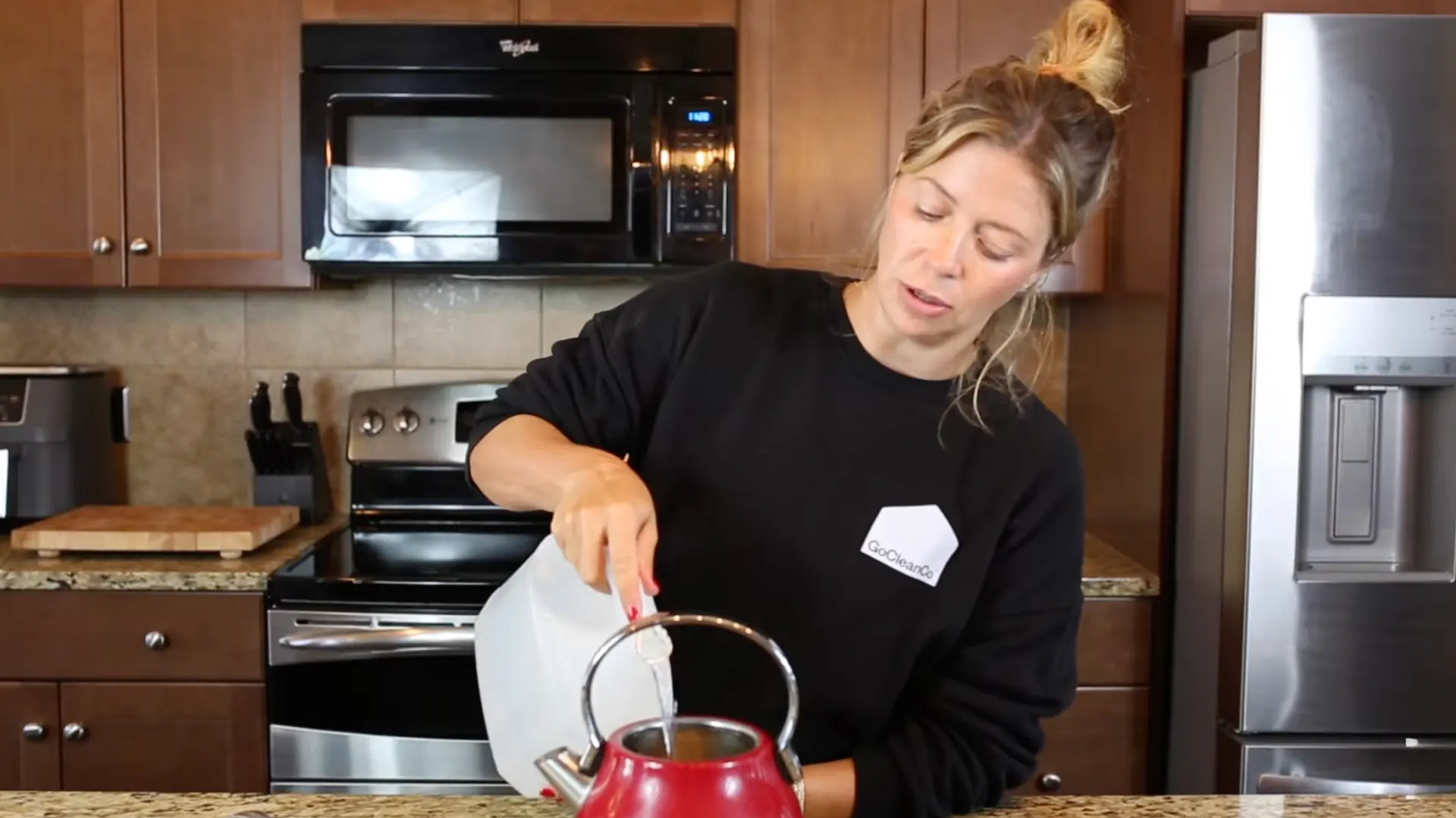 Pouring vinegar and water into a red kettle to remove limescale buildup naturally