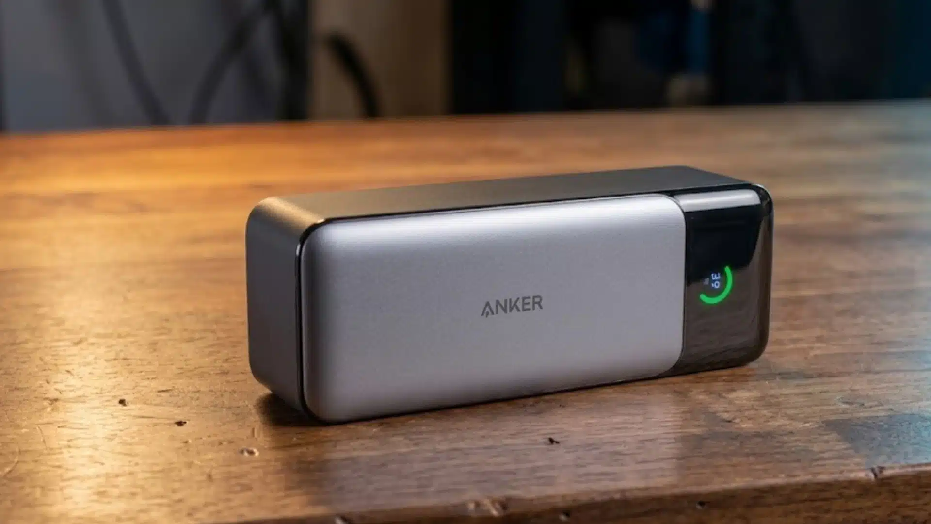 Anker portable power bank with smart battery display resting on a wooden desk indoors