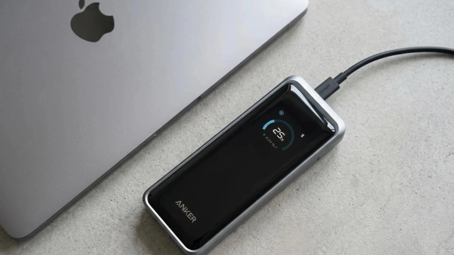 Anker power bank with smart charging display connected to a MacBook through a USB-C cable