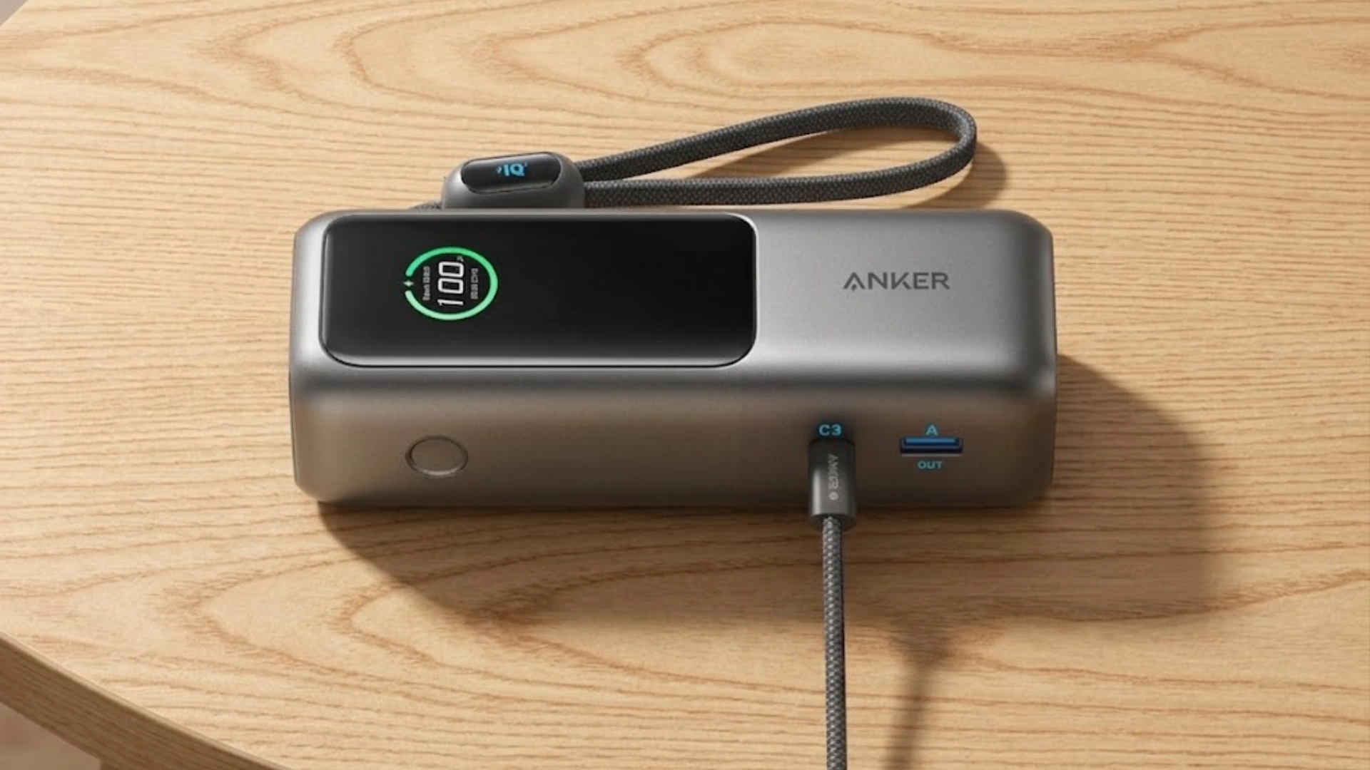 Anker power bank with smart display and built-in cable placed on a light wooden table indoors