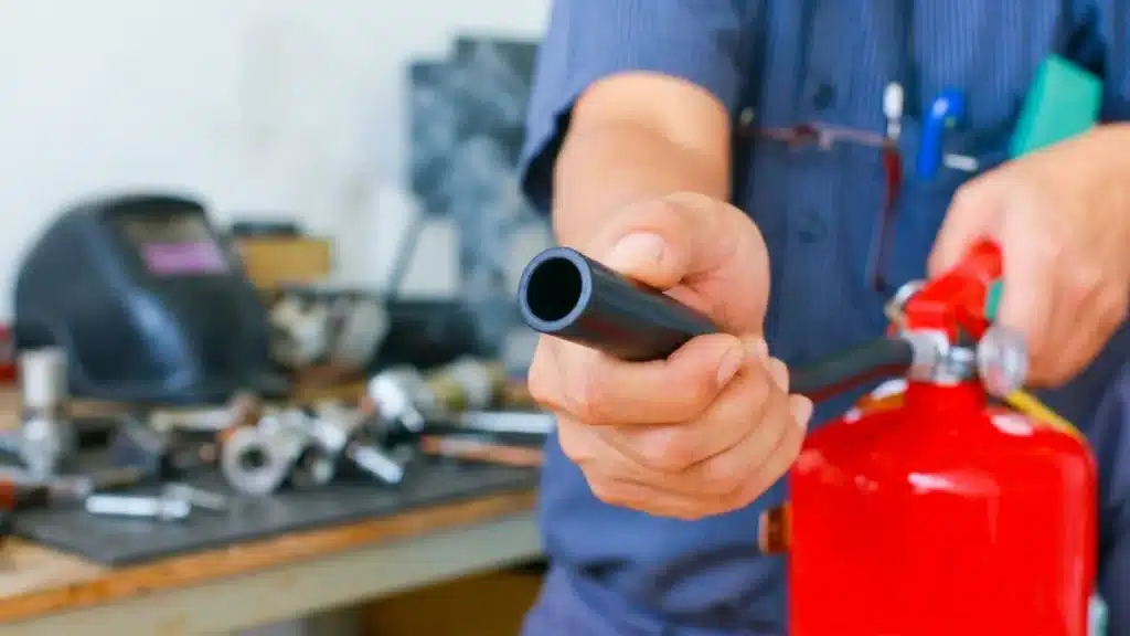 Close-up of a fire extinguisher nozzle held by a worker during safety equipment training