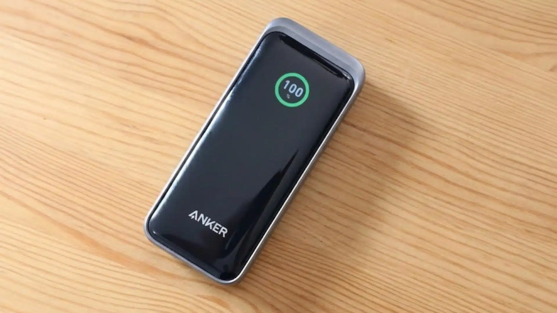 Compact Anker power bank with glossy smart display placed on a light wooden surface indoors