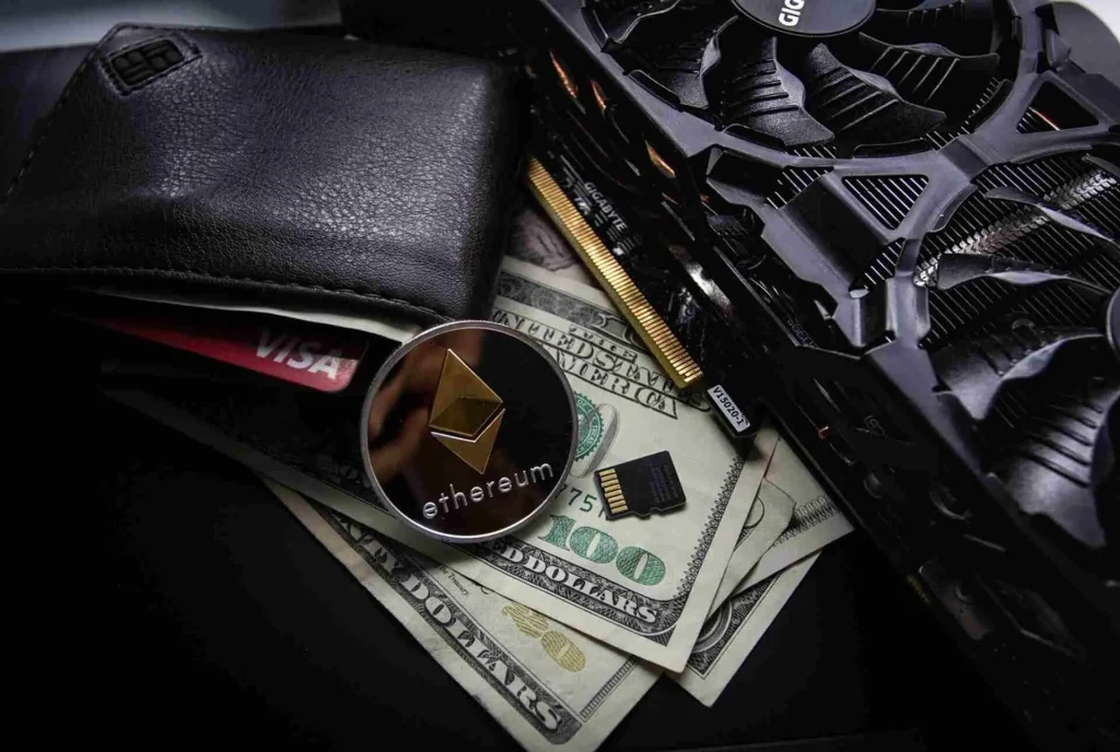 Ethereum coin on US dollar bills beside graphics card and wallet