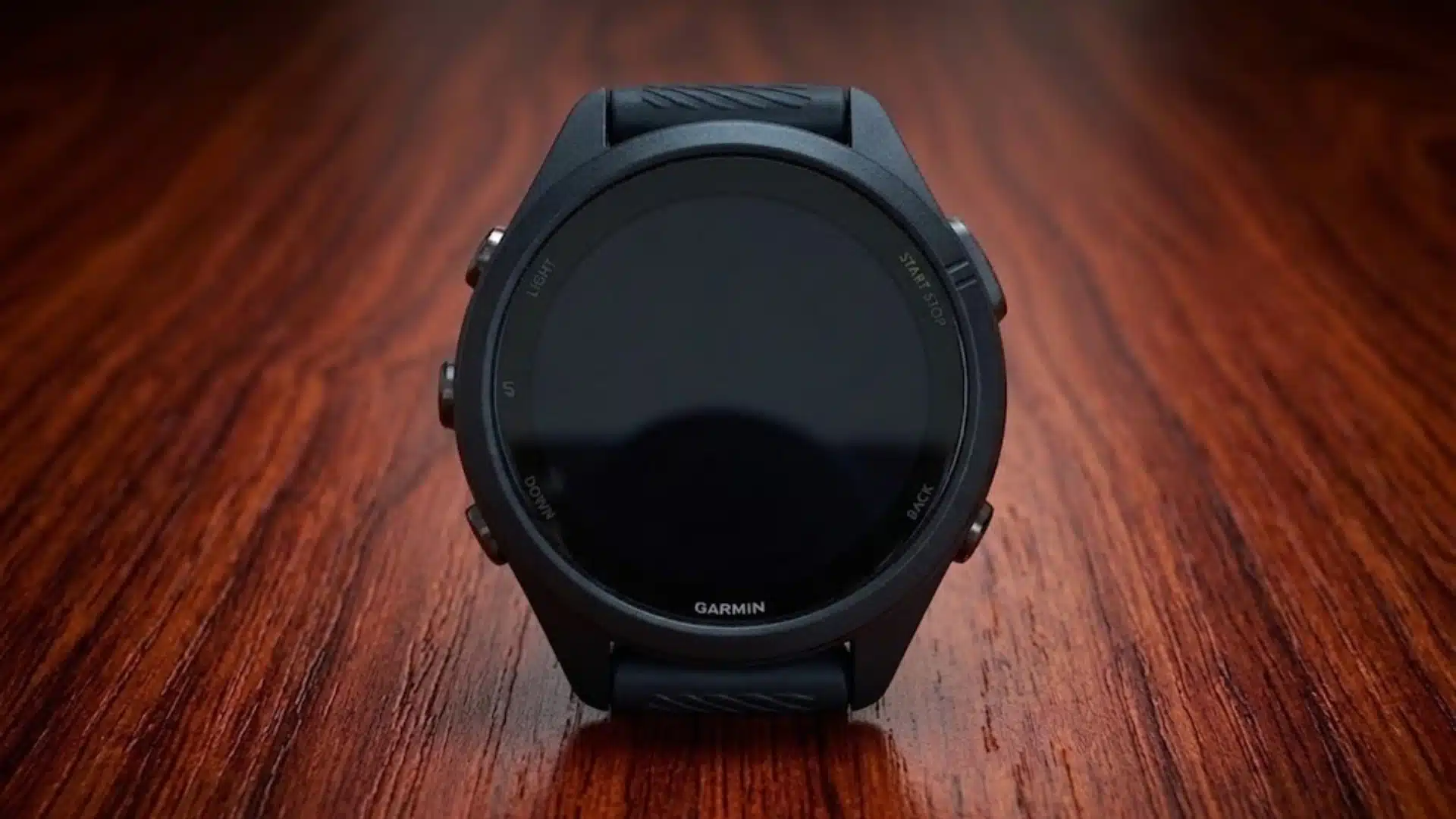 Garmin Forerunner 265 front view with black case and buttons, placed on wooden surface showing clean and minimal design