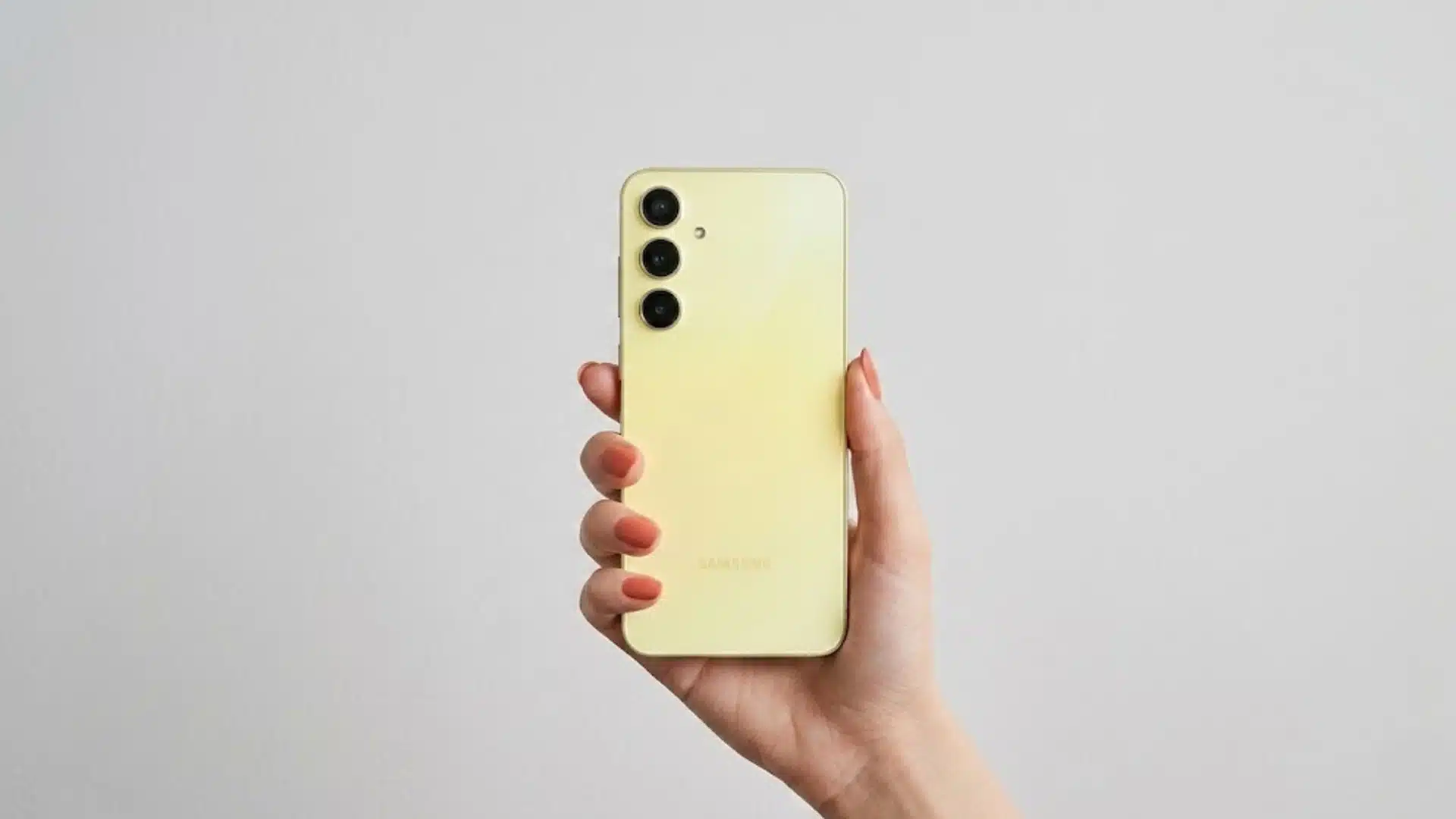 Hand holding a yellow Samsung Galaxy A55 5G smartphone showing the rear triple camera setup
