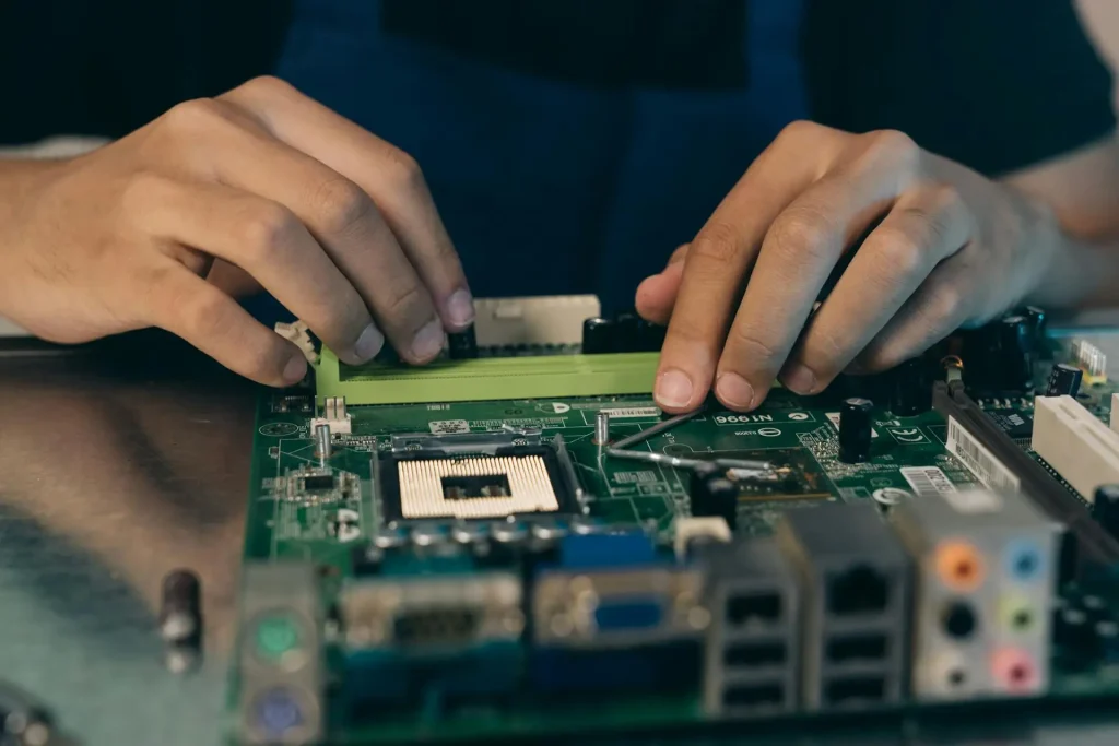 Hands assembling computer motherboard on metallic table in a workshop setting