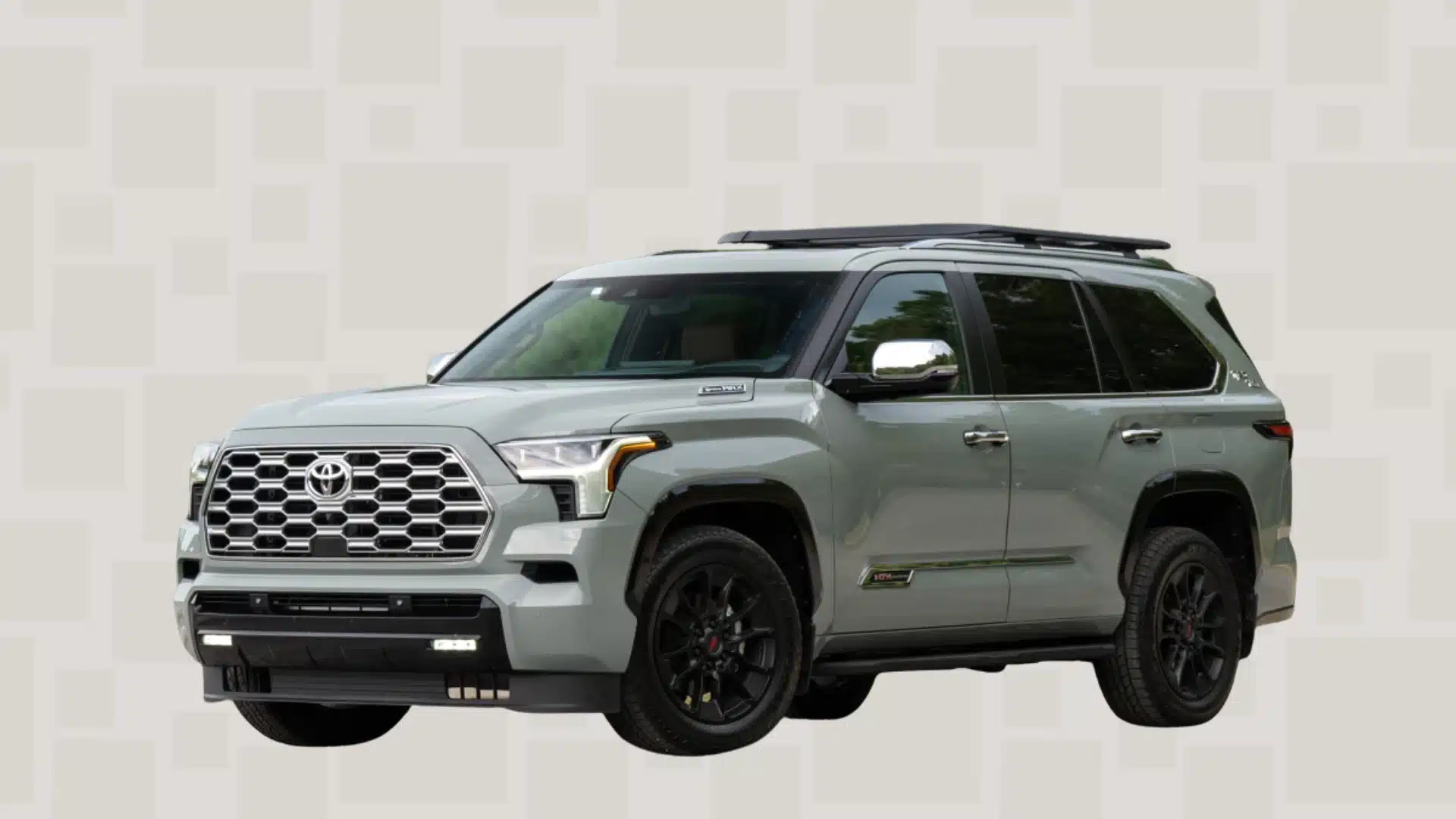 Light gray Toyota Sequoia SUV with black wheels, roof rails, and large front grille displayed at an angle on a patterned gray background