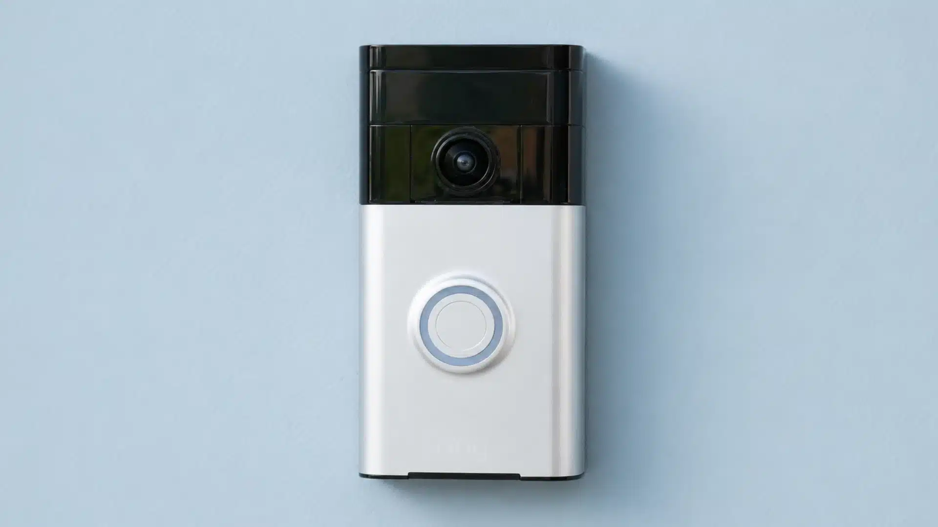 Modern Ring video doorbell mounted on a light blue wall with camera lens and button clearly visible