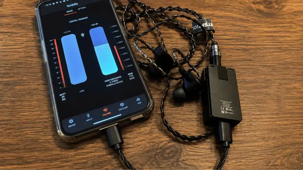 Qudelix 5K portable DAC amp connected to smartphone with wired IEMs and EQ control app interface displayed on screen