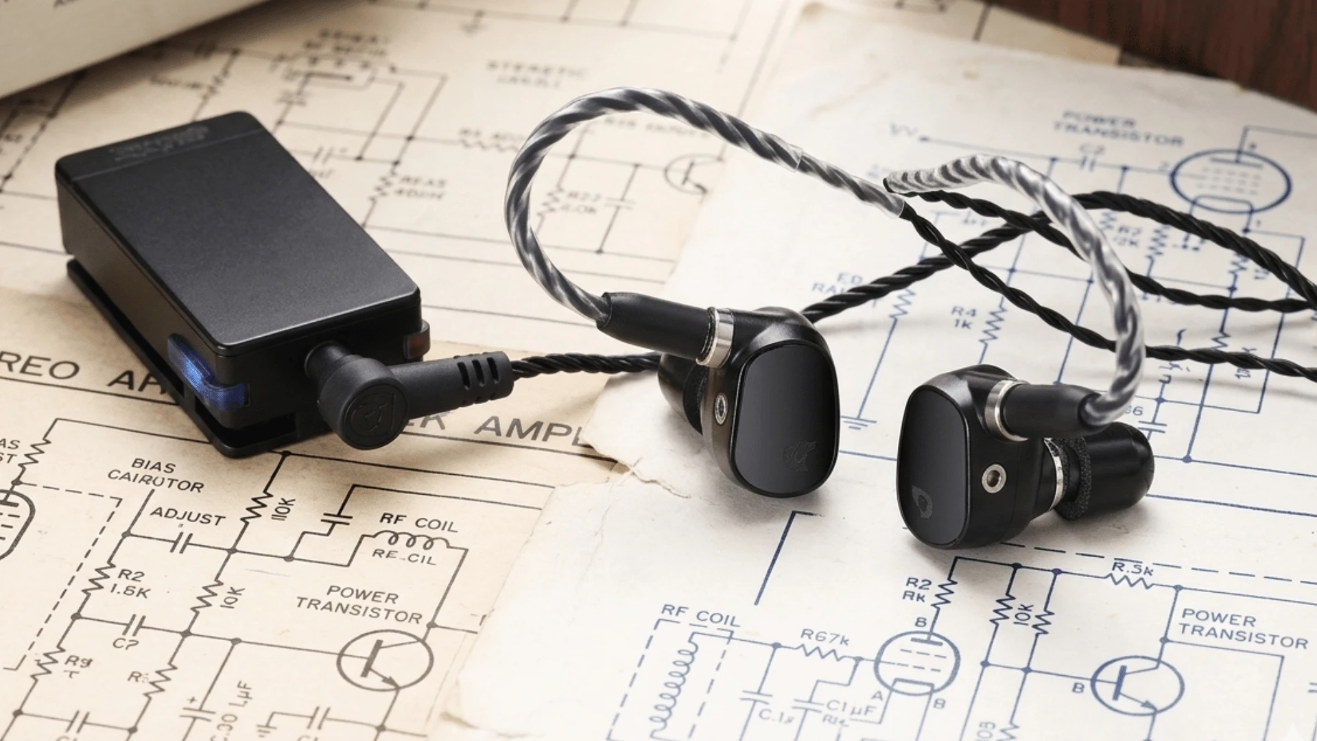 Qudelix 5K portable DAC amp paired with wired IEMs on electronic circuit schematic background