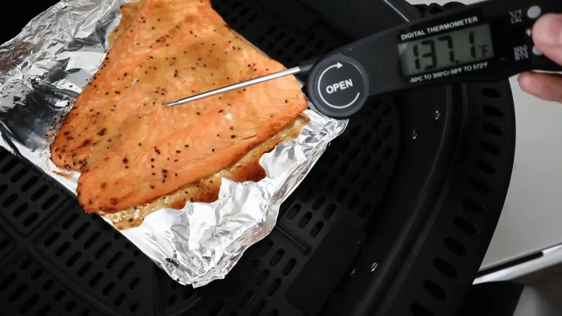 Salmon fillet in air fryer checked with digital thermometer showing safe cooked temperature
