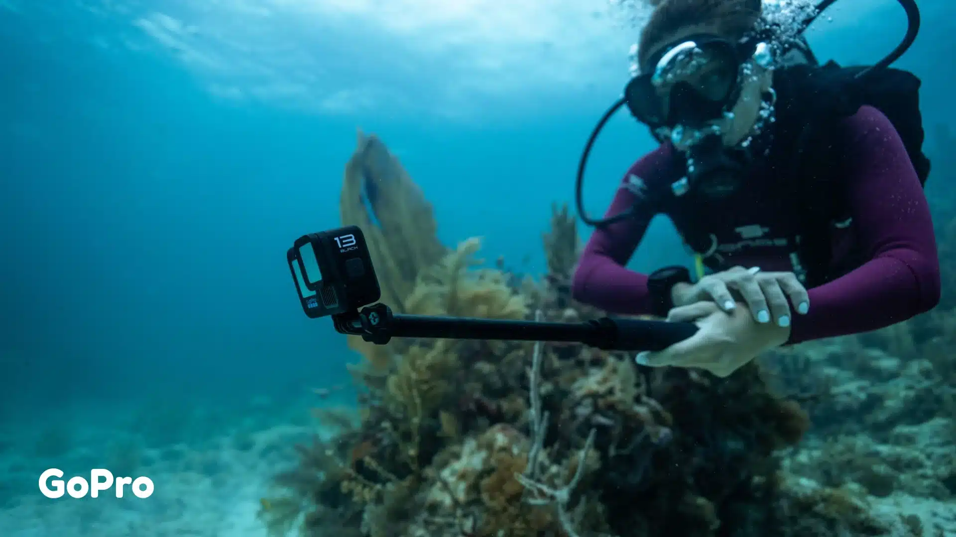 Scuba diver recording underwater footage with a GoPro HERO13 Black action camera and selfie stick