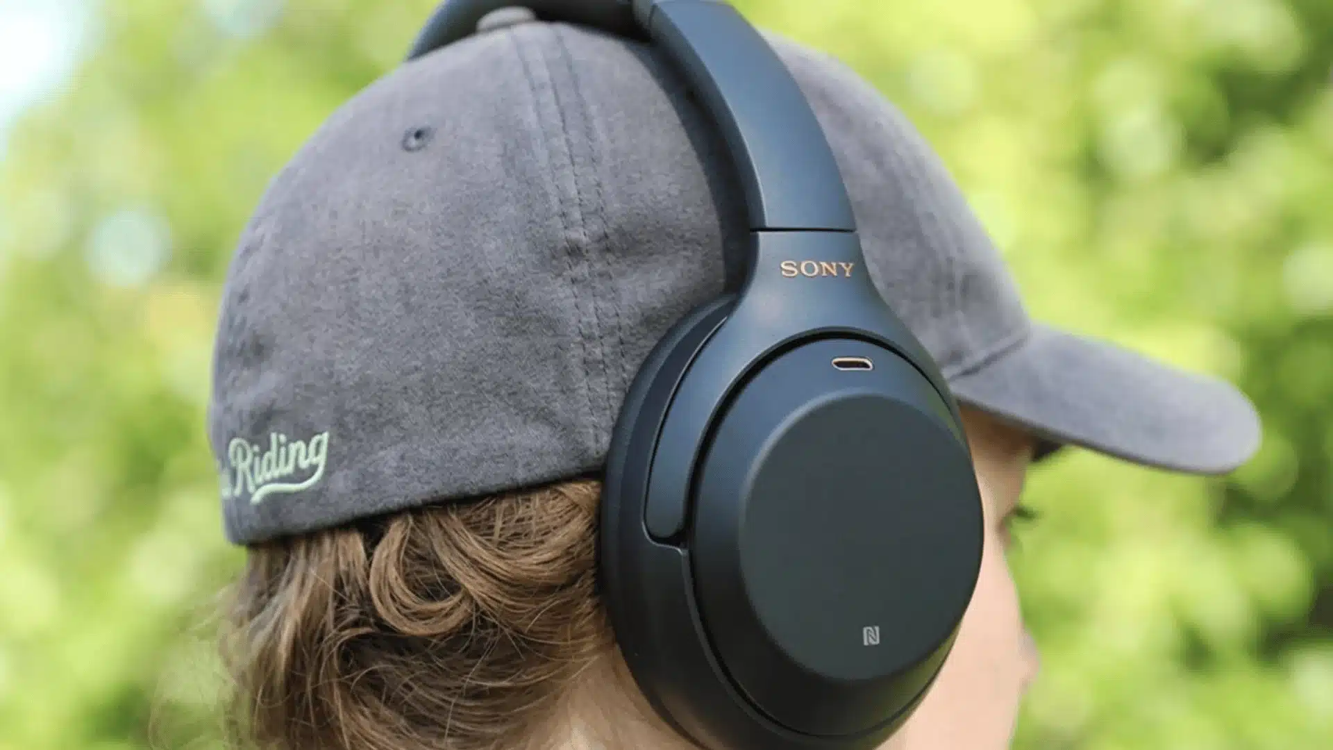 Sony WH-1000XM3 headphones worn outdoors with gray cap, highlighting comfort and noise canceling performance
