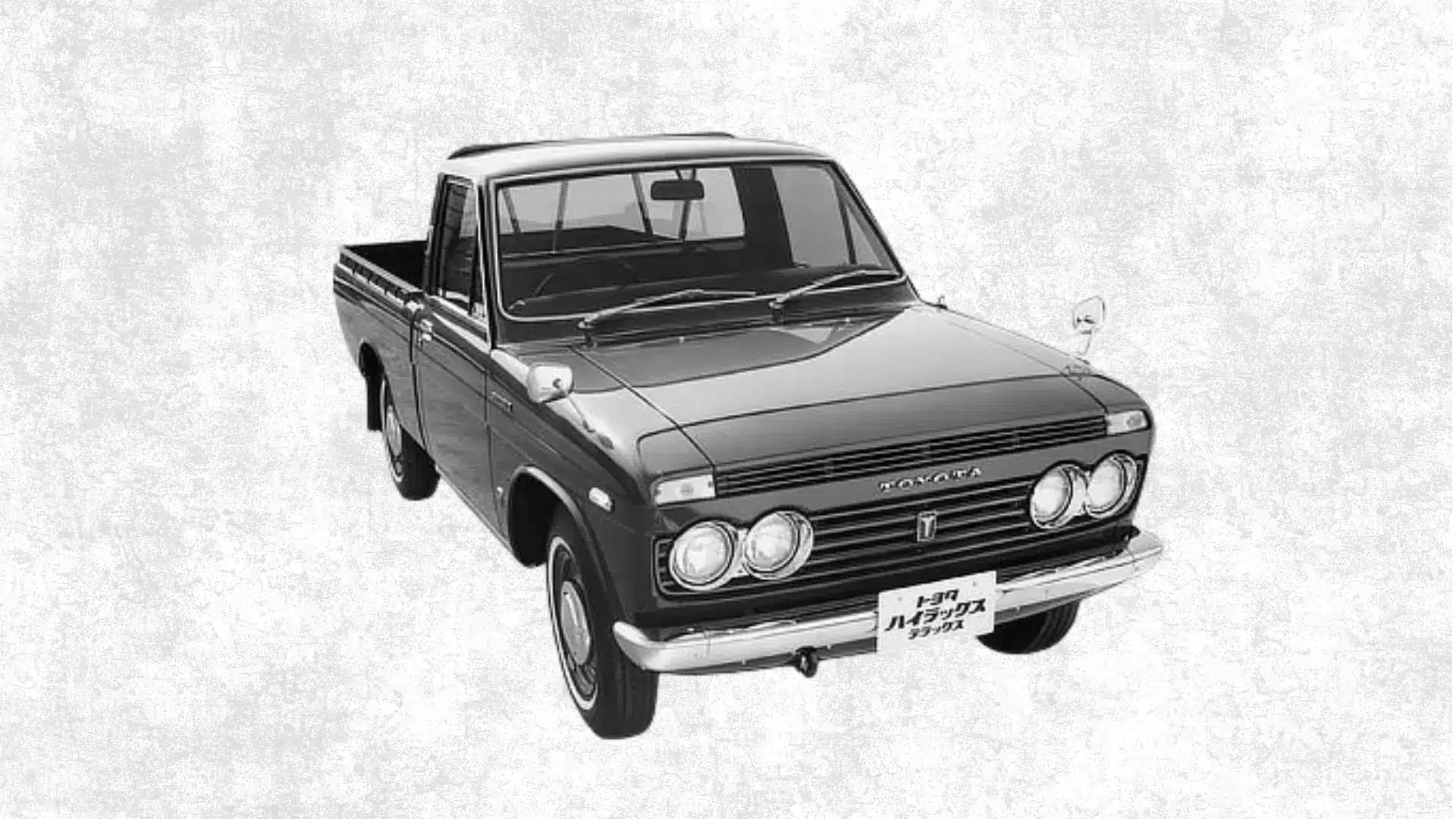 Vintage black Toyota pickup truck with round headlights and chrome bumper shown from a front angle on a textured white background