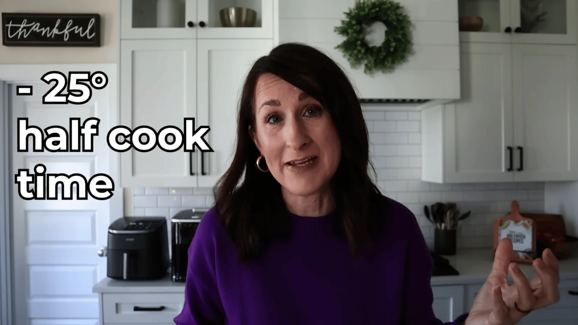 Woman explaining air fryer cooking tip with kitchen appliances in background