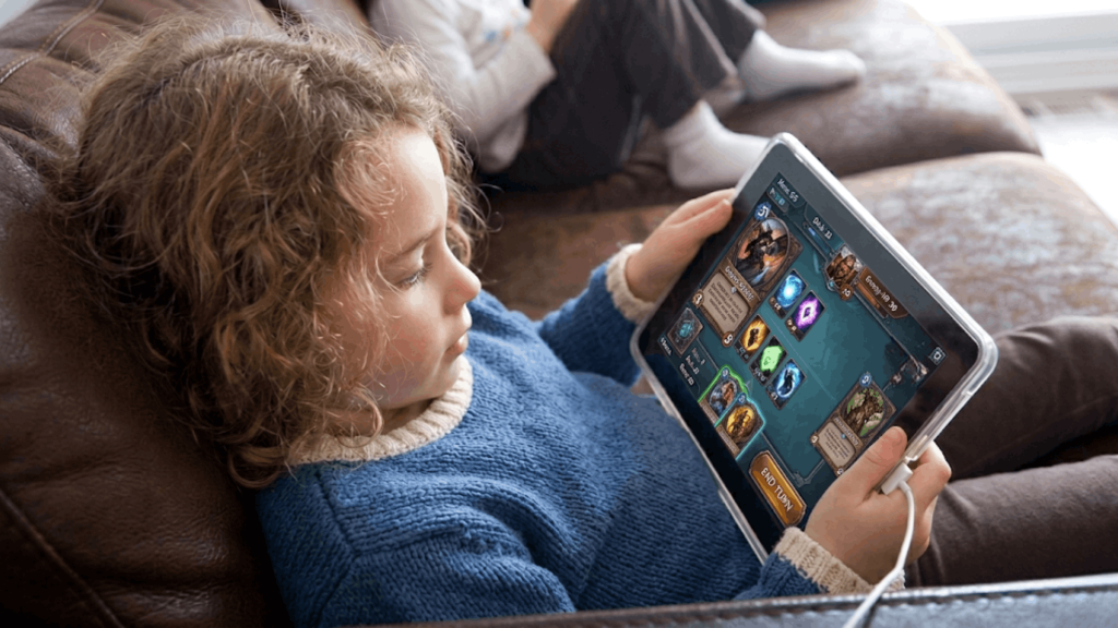 young child playing a game on a tablet while relaxing on a couch at home (1)