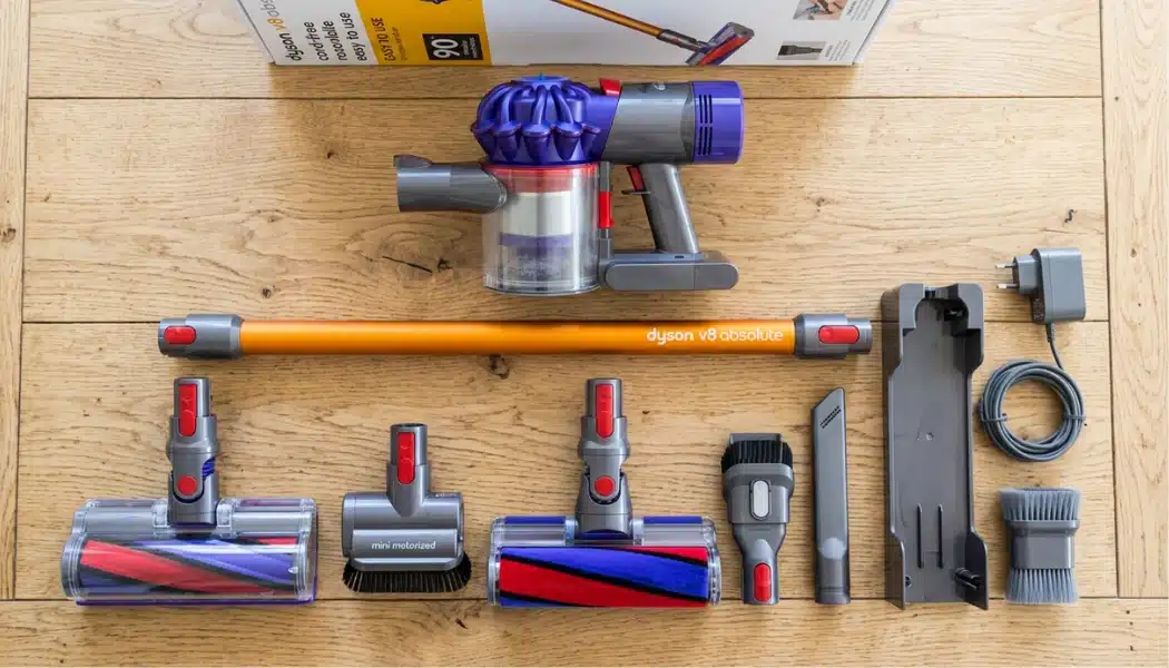 Dyson V8 Absolute vacuum and attachments laid out on a wooden floor