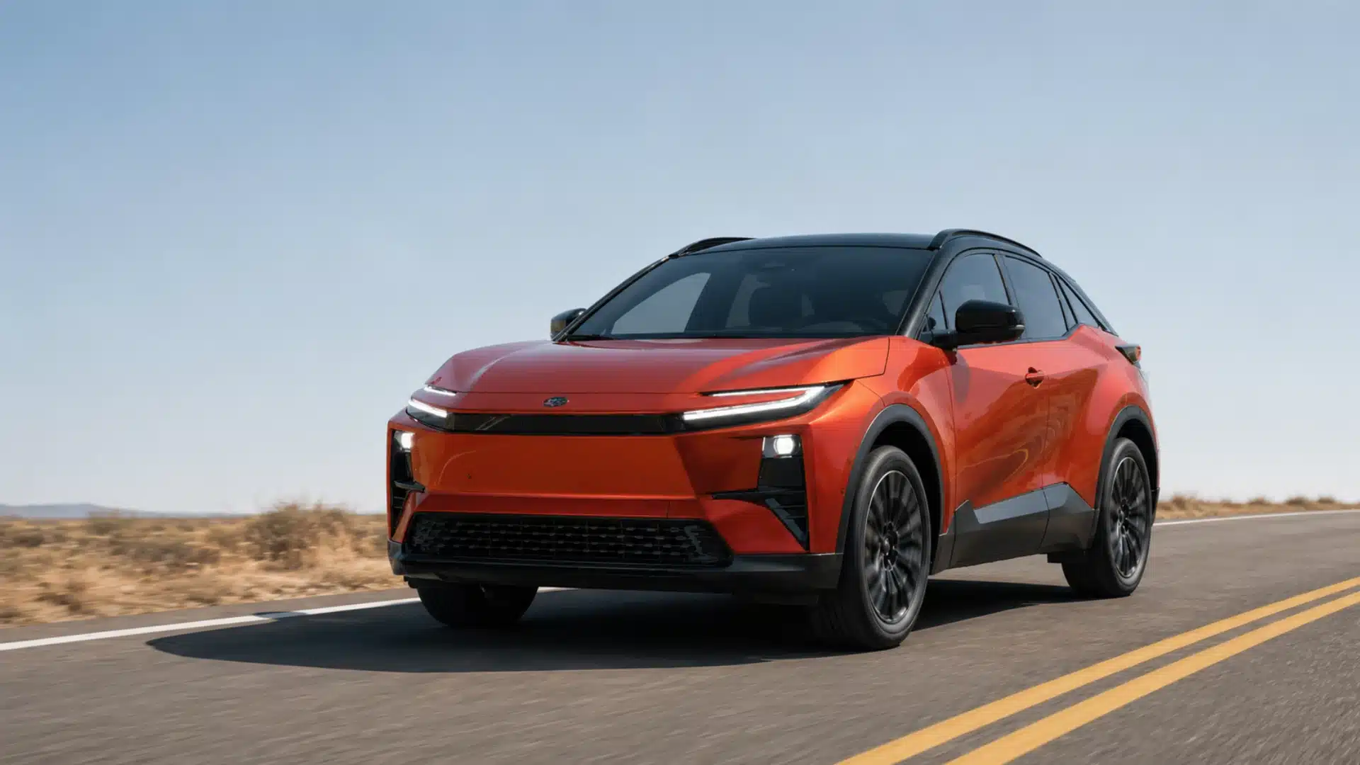 Orange Toyota C HR electric SUV driving on a minimal open road under a clear daytime sky