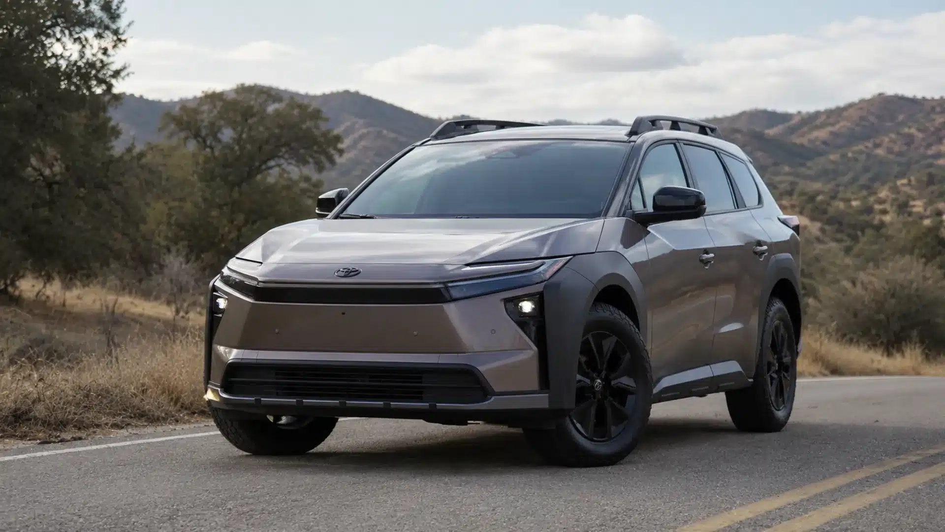 Toyota bZ Woodland electric SUV parked on a scenic mountain road with rugged outdoor styling