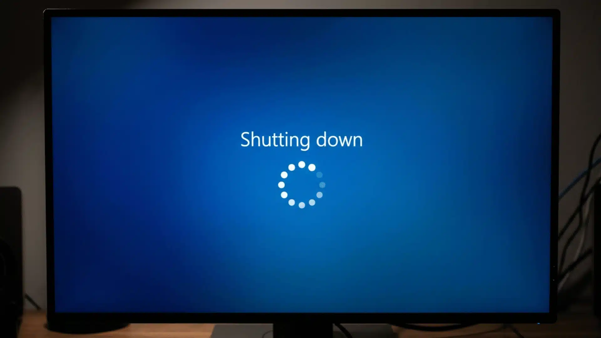 A close-up shot of a computer monitor displaying a blue screen with a loading wheel saying shutting down