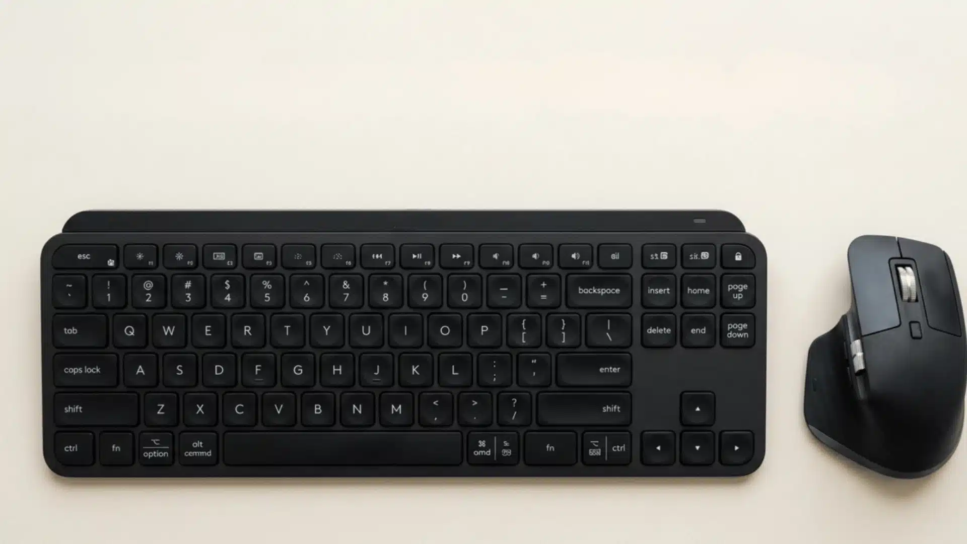 A modern black wireless keyboard and an ergonomic black wireless mouse laid flat on a smooth, beige surface