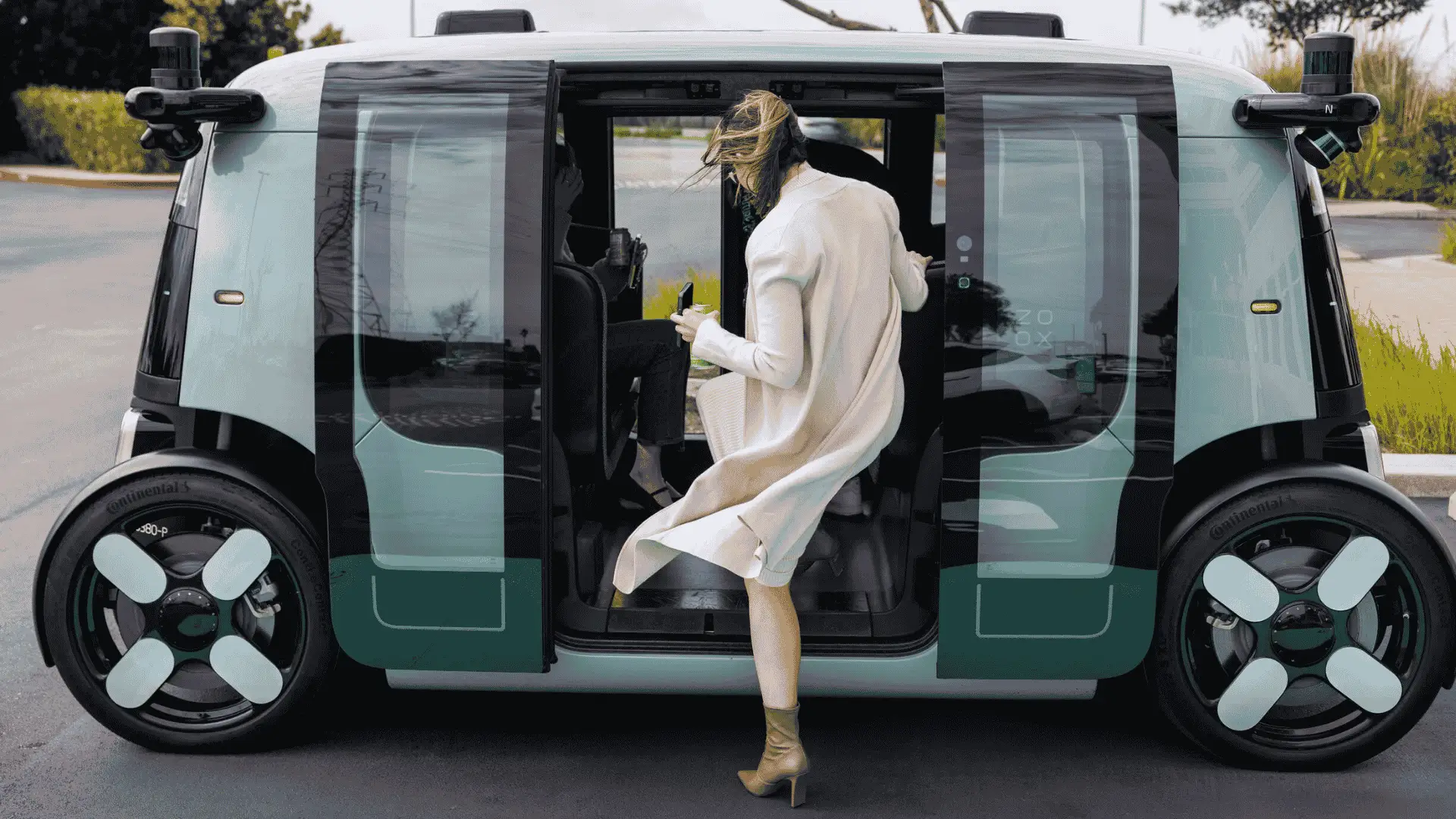 Amazon Zoox autonomous robotaxi with sliding doors as passenger enters futuristic self driving EV