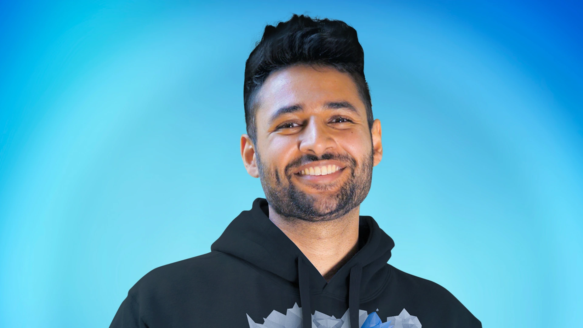 Arun Maini (Mrwhosetheboss) in a black hoodie smiling against a bright blue background