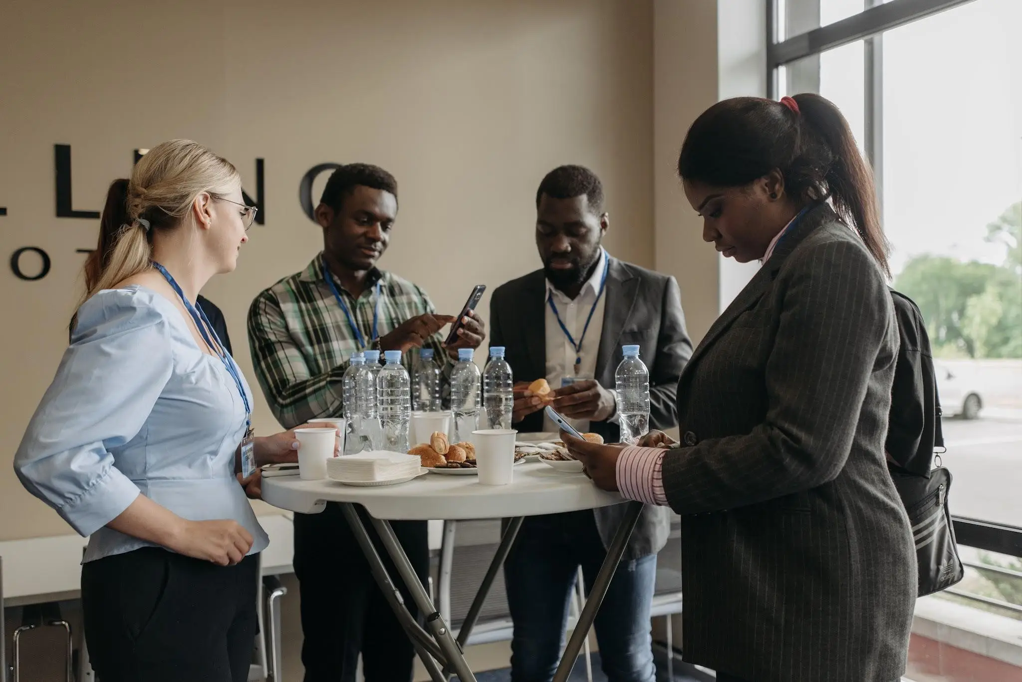 Group of professionals networking at a conference table with drinks and snacks