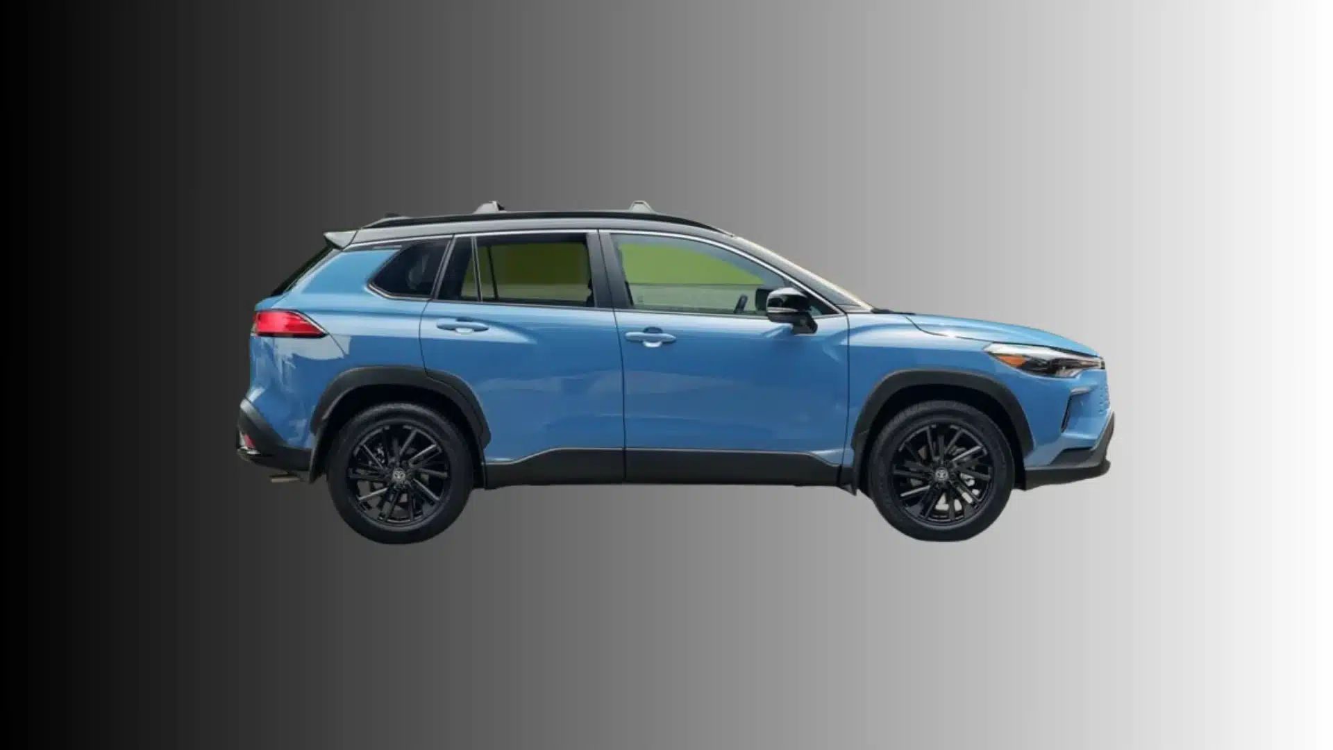 Blue Toyota Corolla Cross SUV shown in side profile with black wheels and roof rails on gray background