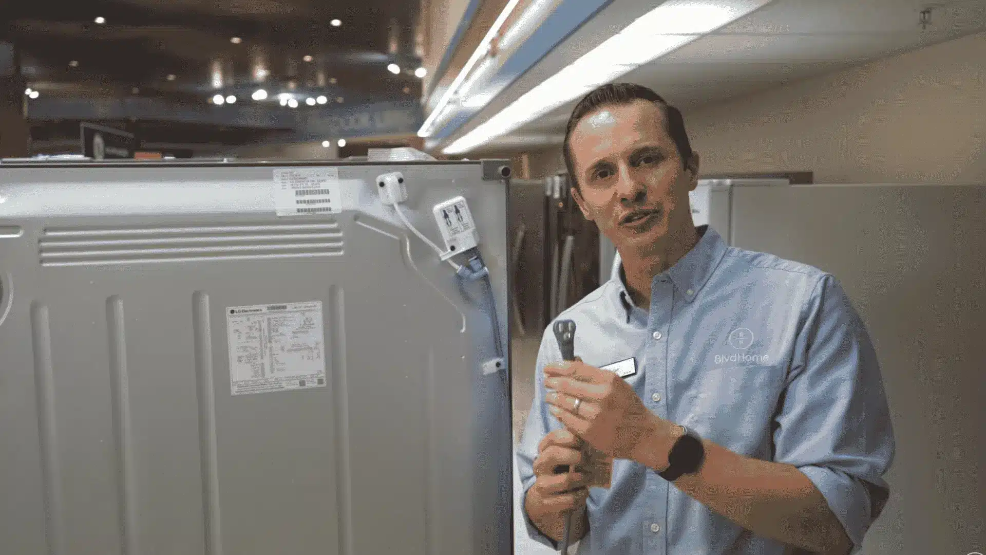 BoulevardHome technician inspecting the refrigerator water supply line for kinks or flow issues behind unit