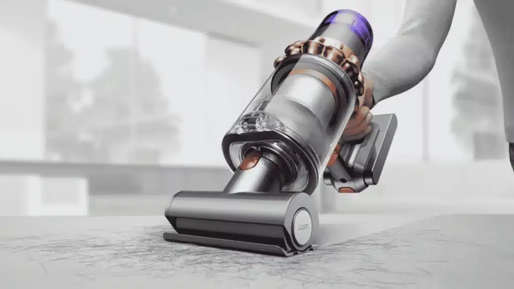 Dyson V11 cordless vacuum using a motorized attachment to remove pet hair from upholstery in a bright room