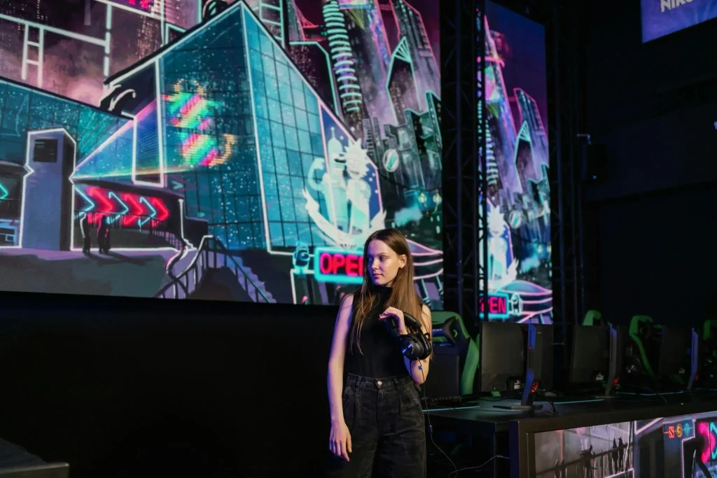 Woman in black outfit standing at gaming event with futuristic digital backdrop