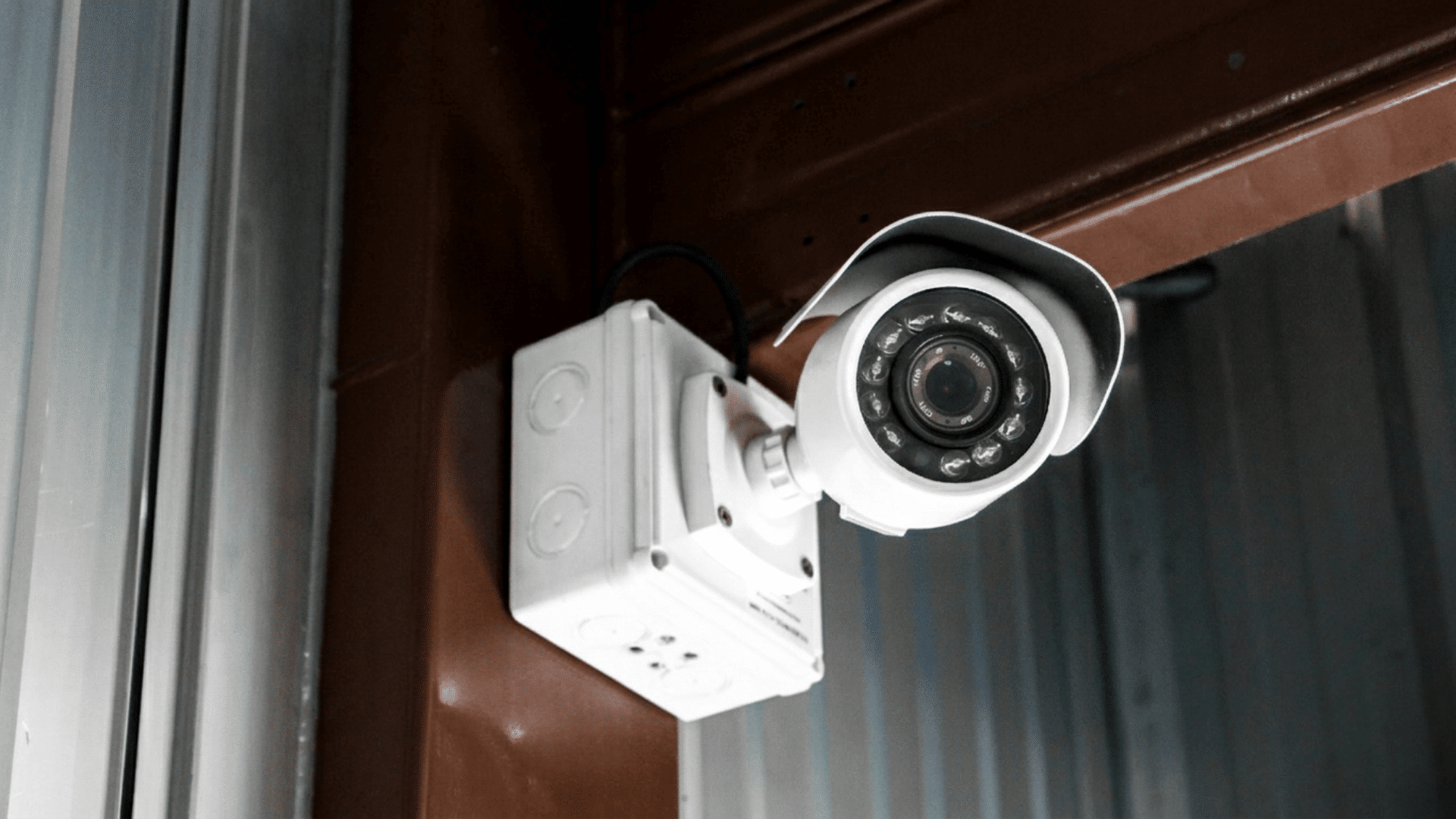 ip security camera mounted outside on a wall near a doorway with protective cover and night vision lights
